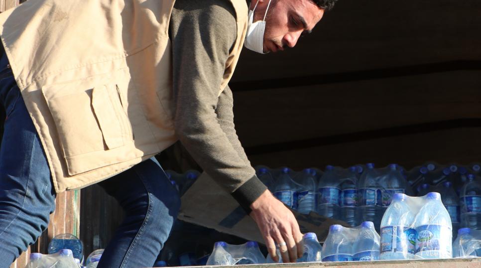 Aid worker handing bottles to those devastated by earthquakes in Turkey and Syria