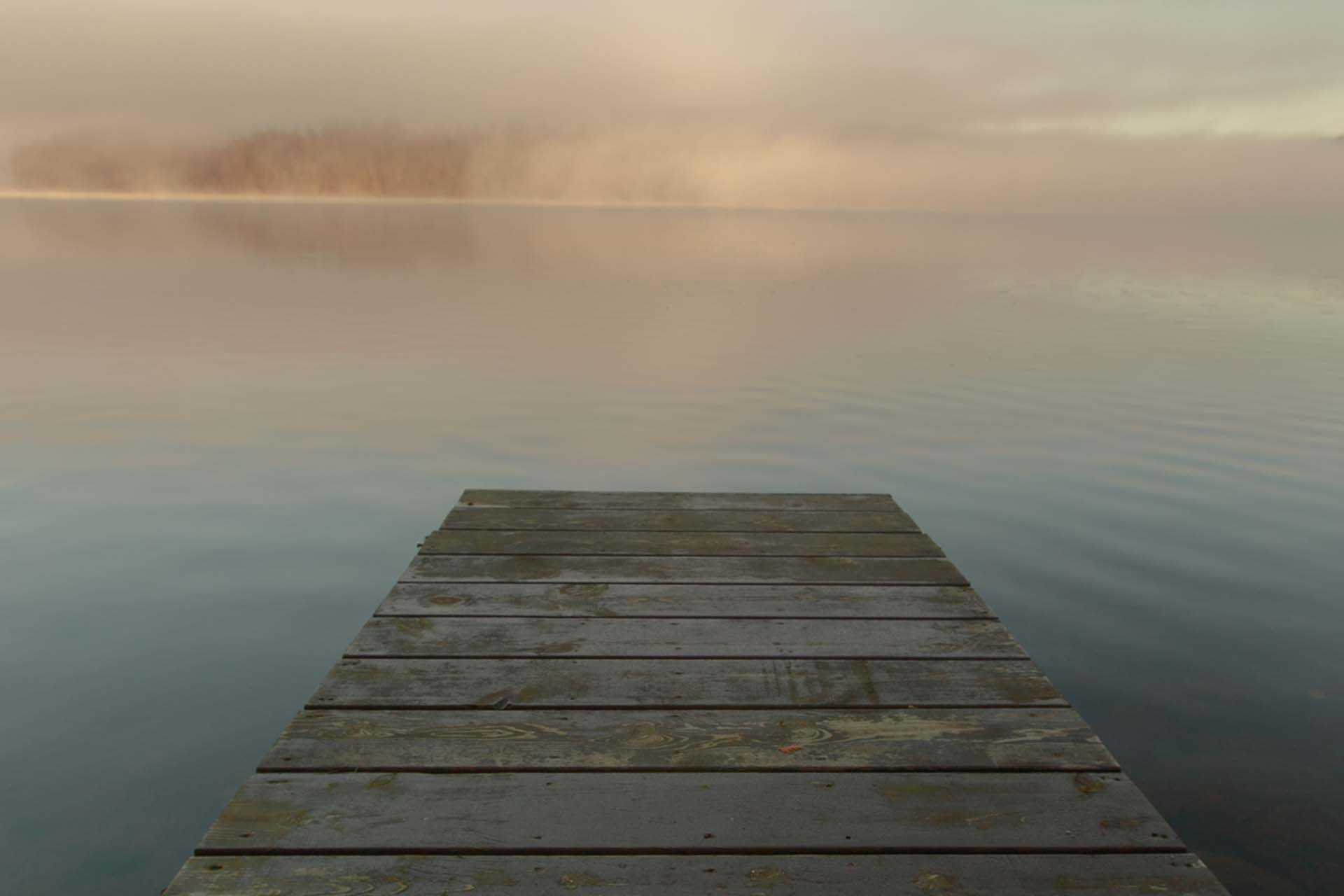 Wooden pontoon into a still lake