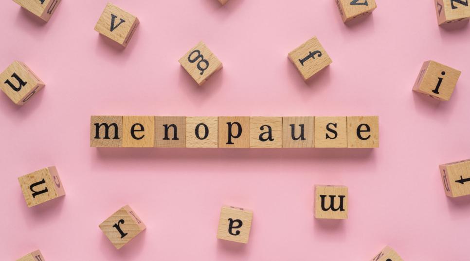Scrabble tiles spelling out menopause on a pink background