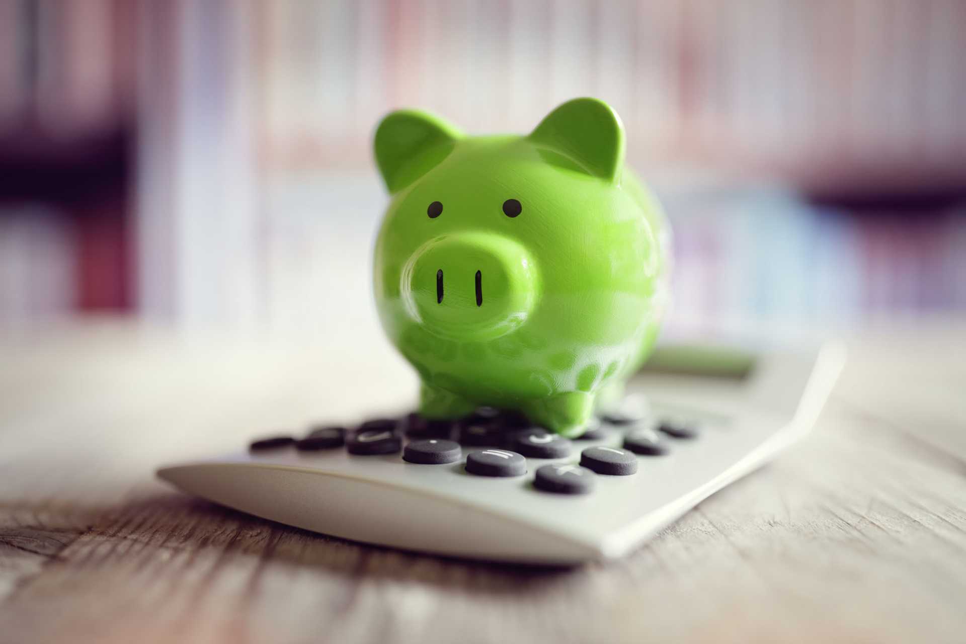 Image of a green piggy bank sitting on a calculator