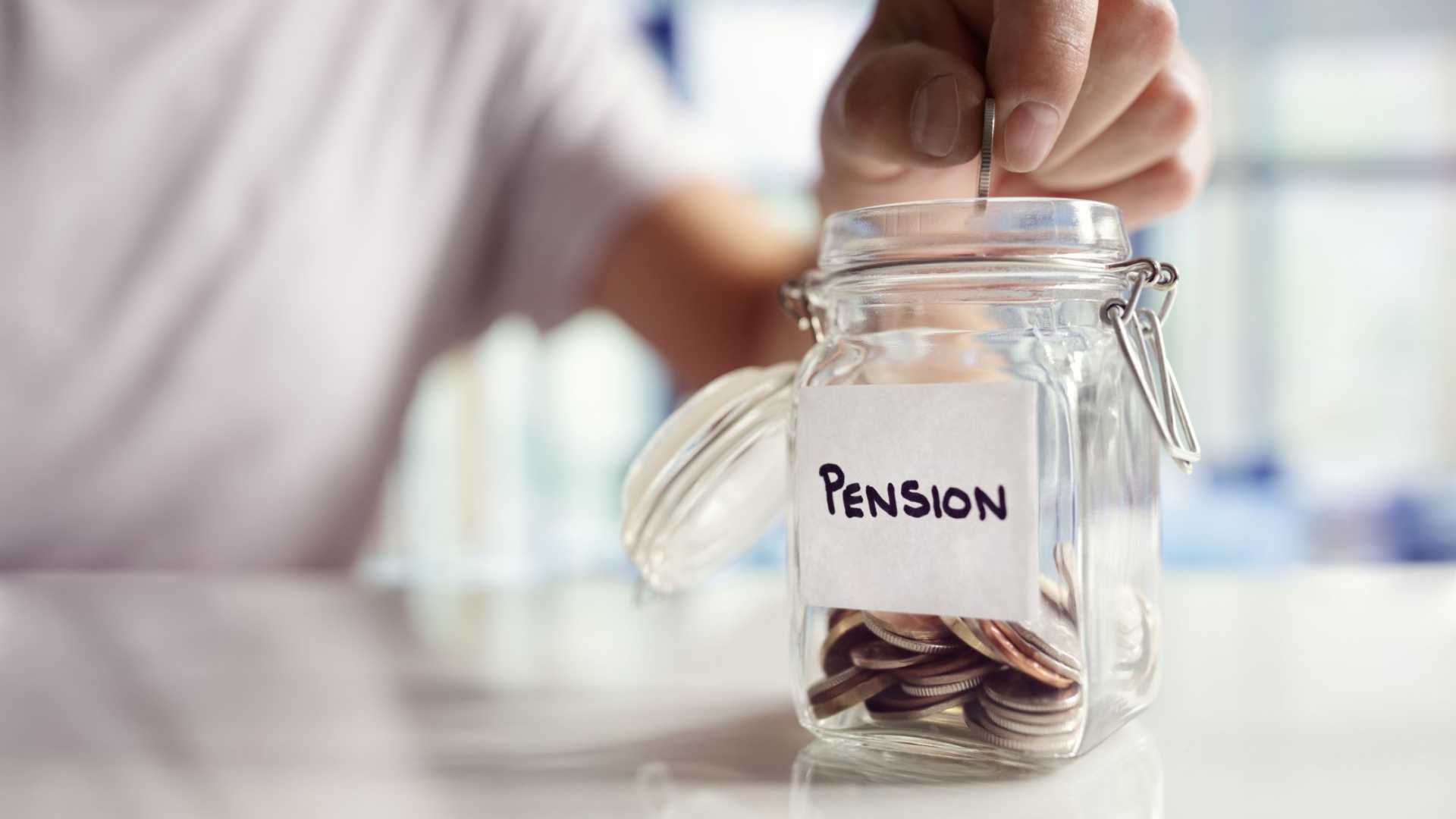 A hand putting money into a glass jar marked 'Pension'