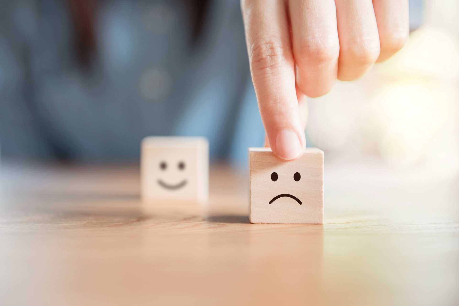 Image of wooden blocks with smiley face blurred and sad face in focus