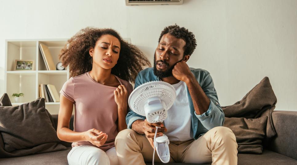 Two people looking uncomfortably warm with a fan between them